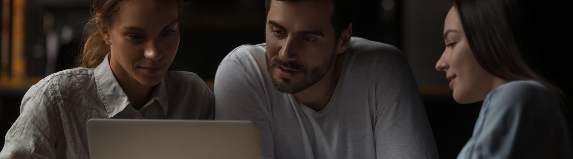 Three people examining laptop